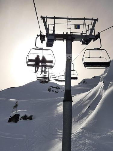 two people riding on a ski lift in the snow at Appartement Berghof "Dettis Place" in Gerlos