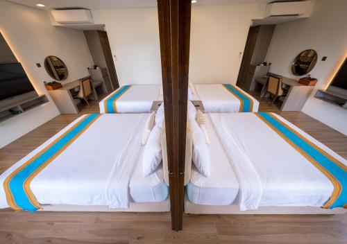 two beds in a hotel room with white beds at Magarra Hotel in Orani