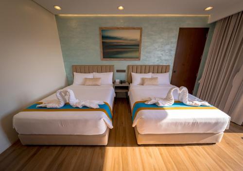 two beds in a hotel room with towels on them at Magarra Hotel in Orani