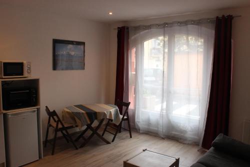 un salon avec une table et des chaises et une fenêtre dans l'établissement Studio meublé entièrement équipé, à Elne