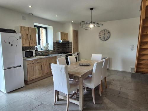 - une cuisine avec une table en bois et des chaises blanches dans l'établissement L'Abaca 23, à Sainte-Geneviève-lès-Gasny