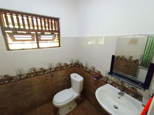 Un baño con inodoro, lavabo y ventana. en Benefit Villa Mirissa, en Mirissa