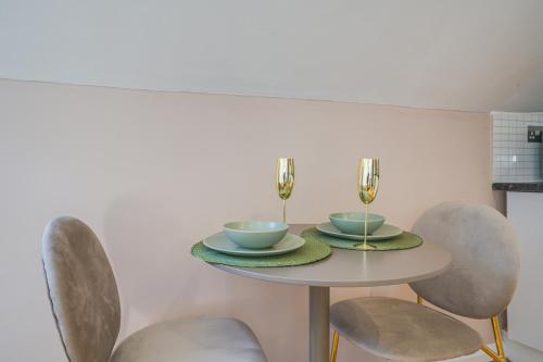 a dining room table with two bowls and chairs at 7even Clouds Oasis- Stylish Apartment Near Westfield in London