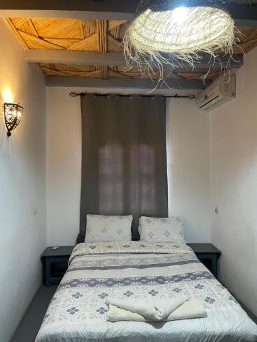 a bedroom with a bed with a chandelier above it at Etoile d Or Ksar Ait Ben Haddou in Aït Ben Haddou