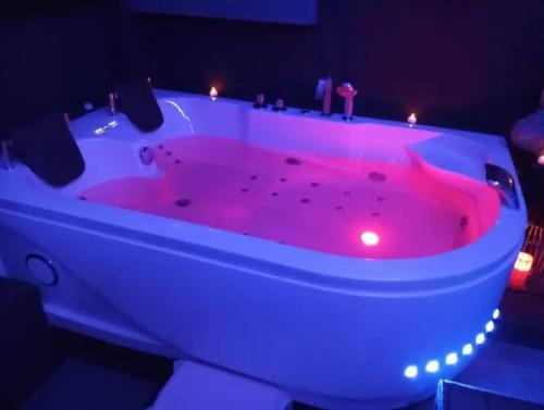 une baignoire rose avec des lumières dans la chambre dans l'établissement Maison SPA Privatif, à La Celle-sous-Gouzon