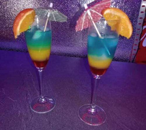 deux cocktails avec des oranges et un parasol sur une table dans l'établissement Maison SPA Privatif, à La Celle-sous-Gouzon