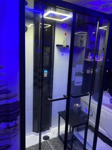 une douche avec un banc dans une pièce avec des lumières bleues dans l'établissement Maison SPA Privatif, à La Celle-sous-Gouzon
