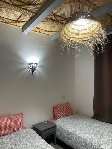a room with two beds and a light on the wall at Etoile d Or Ksar Ait Ben Haddou in Aït Ben Haddou