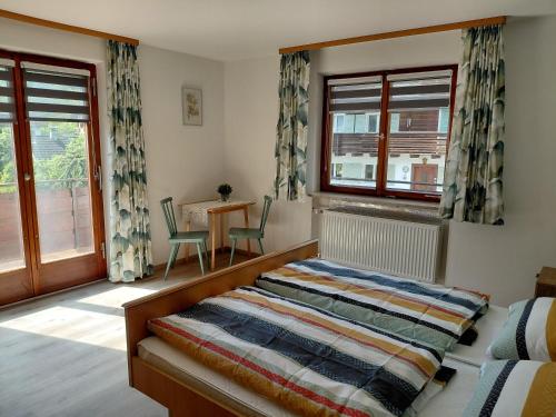 a bedroom with a bed and a table and windows at Ferienhaus Gioia in Schruns-Tschagguns