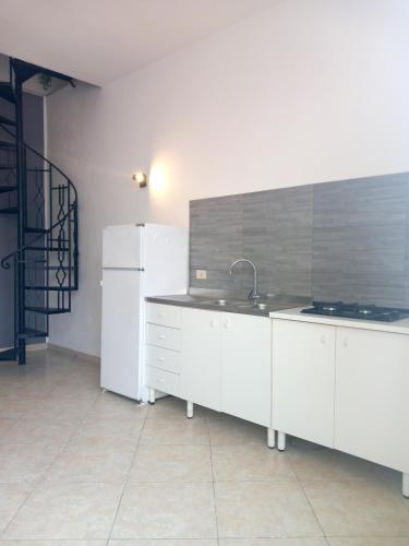 a white kitchen with a sink and a refrigerator at Tahiti House Stagnone in Marsala