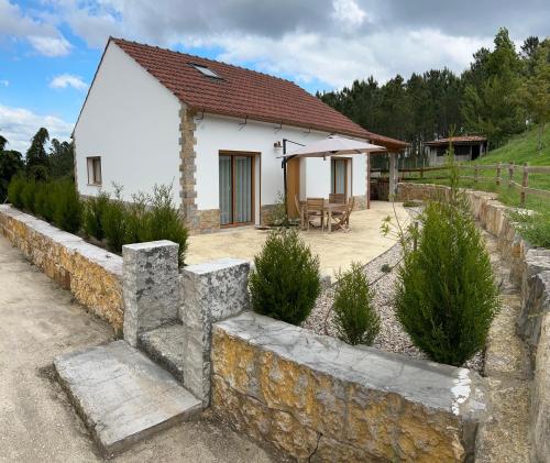 a small white house with a stone wall at Jardins do Barão in Leiria