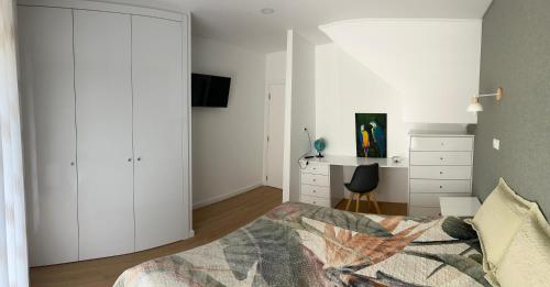 a bedroom with white walls and a bed and a desk at Jardins do Barão in Leiria