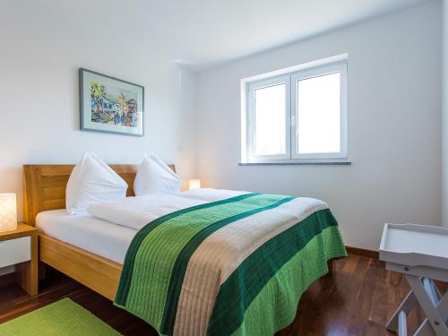 a bedroom with a bed with a green and white blanket at Apartment Maestral in Poreč