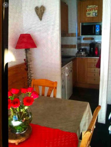 une cuisine avec une table et un vase avec des fleurs rouges. dans l'établissement Cozy Duplex Terrasse plein sud, à Puy-Saint-Vincent