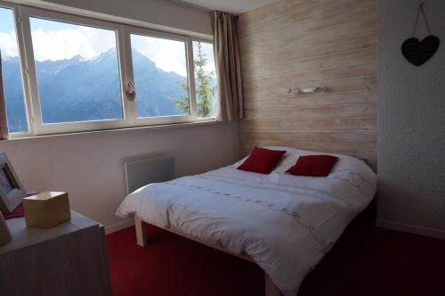 une chambre avec un lit avec des oreillers rouges et une fenêtre dans l'établissement Cozy Duplex Terrasse plein sud, à Puy-Saint-Vincent
