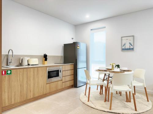 a kitchen with a table and chairs and a refrigerator at Casa Lumi Walk to Marina & Beach in Shellharbour