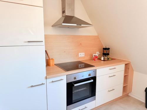 a small kitchen with white cabinets and a stove at Le Duplex des Tulipes - Parking included - Haguenau in Haguenau