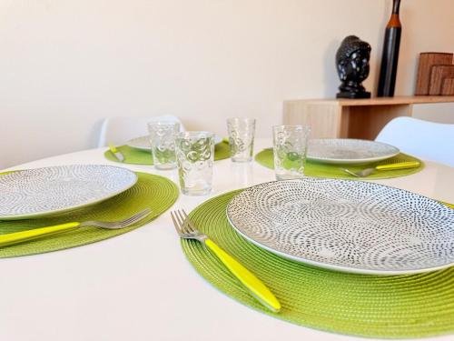 a white table with green plates and forks and napkins at Le Duplex des Tulipes - Parking included - Haguenau in Haguenau