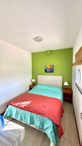 a bedroom with green walls and a bed with a red blanket at Container Serrano in San Gerónimo