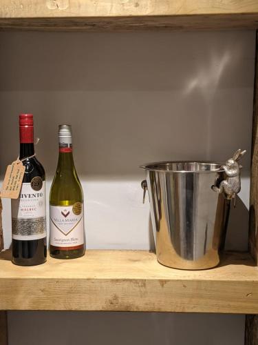 two bottles of wine and a bucket on a shelf at the Nook, Romantic cottage for two, Dartmoor and SW coast in Bovey Tracey