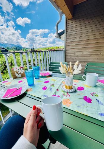 a person sitting at a table with a cup at Berg Fux - Ferienwohnung Louis der Fux in Sonthofen