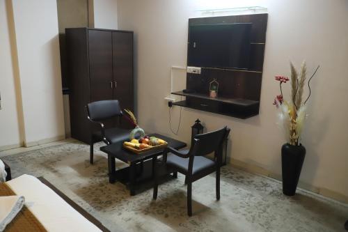 a living room with a table and chairs and a television at Hotel R K Palace - Simple Stay Royal Comfort in Jaipur