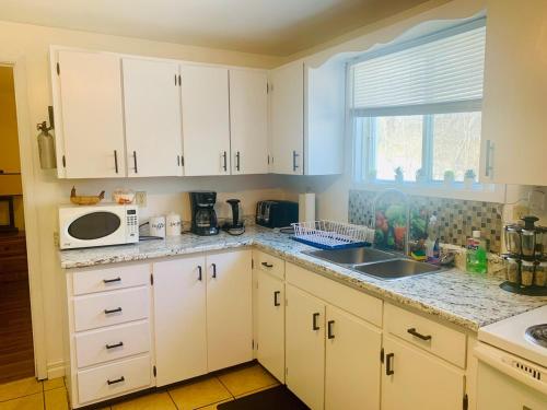 a kitchen with white cabinets and a sink and a microwave at 2 bedrooms home in Kentville in Kentville