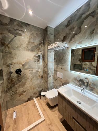 a bathroom with a tub and a toilet and a sink at Kamberi Hotel & Apartments in Velipojë