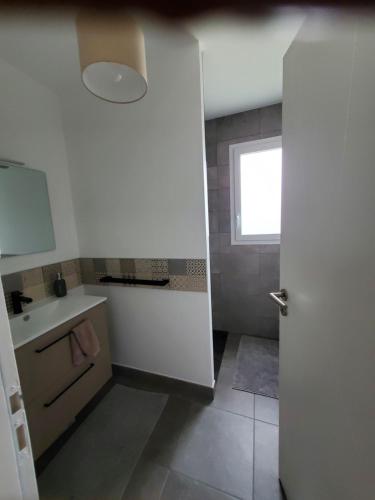 a white bathroom with a sink and a window at Les pivoines Notre-Dame-de-Monts in Notre-Dame-de-Monts