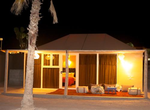 a house with a tent and chairs and a palm tree at Kal Tenere Agafay Luxury Camp in El Karia