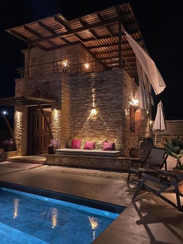 a patio with a bed next to a pool at night at Peroulia Stone Villa Koroni - Grèce, Péloponnèse in Koroni