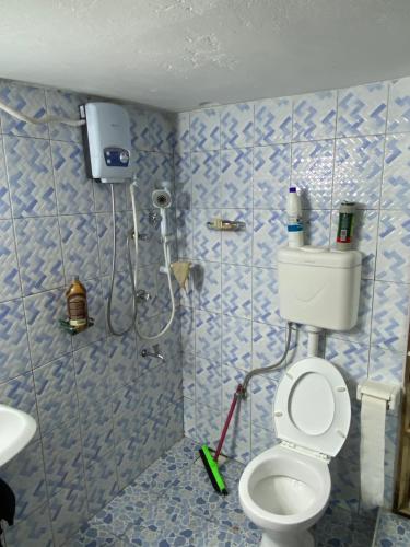 a bathroom with a toilet and a shower with blue tiles at Green Enchantment Home in Nalakonge
