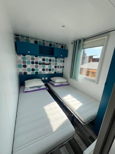 deux lits dans une petite pièce avec une fenêtre dans l'établissement 421 Mobil home domaine de la forge, à La Teste-de-Buch