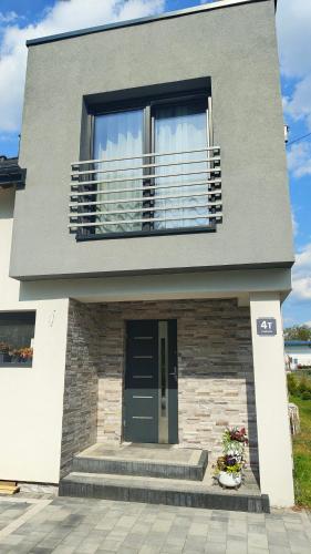 a gray house with a balcony and a door at Domek Liliowe Marzenie in Chrzanów
