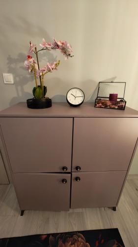 a dresser with a clock and flowers on top of it at Domek Liliowe Marzenie in Chrzanów