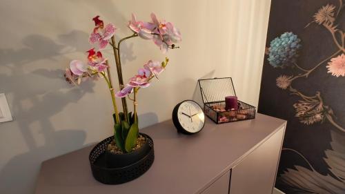 a table with a clock and a vase with flowers on it at Domek Liliowe Marzenie in Chrzanów