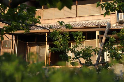 a building with a tree in front of it at 柿畑の宿 guesthouse next to the persimmon orchard in Katsuragi