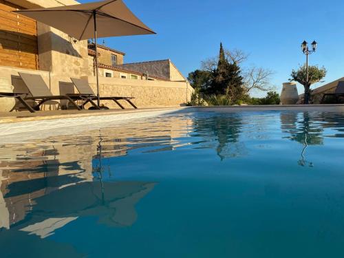 - une piscine avec un parasol et des chaises dans l'établissement Les Granges Saint Paul, à Lespignan