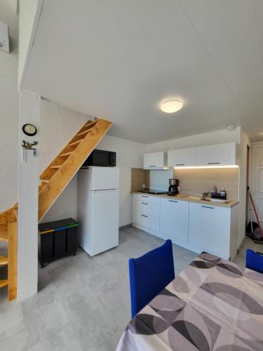 une cuisine avec des placards blancs et une table avec des chaises bleues dans l'établissement appartement avec vue sur l étang de Barcares, au Barcarès