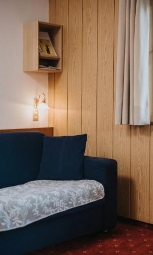 ヴァルダーオラにあるUnterhauserhof App Aの木製の壁の客室内の青いソファ