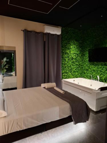 a bedroom with a green wall and a bed and a tub at Dark & Light rooms & luxury suites in Catania