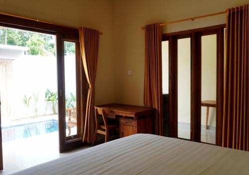 een slaapkamer met een bed, een bureau en een raam bij Made 02 Balangan, Homestay, Villas, & Warung Made02 in Uluwatu