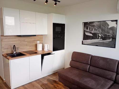 a kitchen with white cabinets and a couch in a room at Moniuszki 4 in Cieszyn