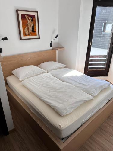 a bed with white sheets and pillows in a bedroom at Apartments Kaninska Vas in Bovec