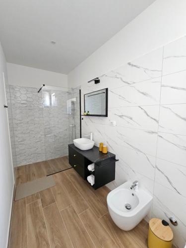 a white bathroom with a sink and a toilet at Apartment Mare Paola in Medulin