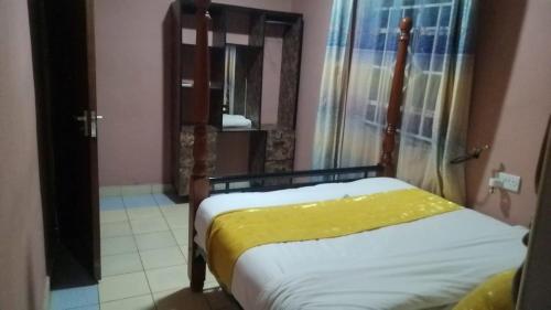 a bedroom with a bed with a yellow blanket on it at Cis Mara Acacia Motel in Narok