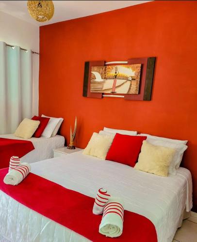 two beds in a room with orange walls and red accents at pousada primavera in São Miguel do Gostoso