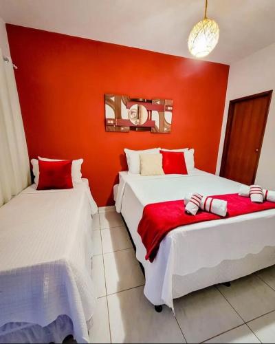 two beds in a room with an orange wall at pousada primavera in São Miguel do Gostoso