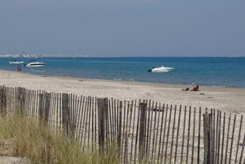 une clôture sur une plage avec des gens dans l'eau dans l'établissement Villa Mimosa Côté Mer et Piscine, à Frontignan