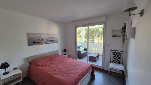 - une chambre avec un lit rouge et un balcon dans l'établissement La Plage, à La Londe-les-Maures